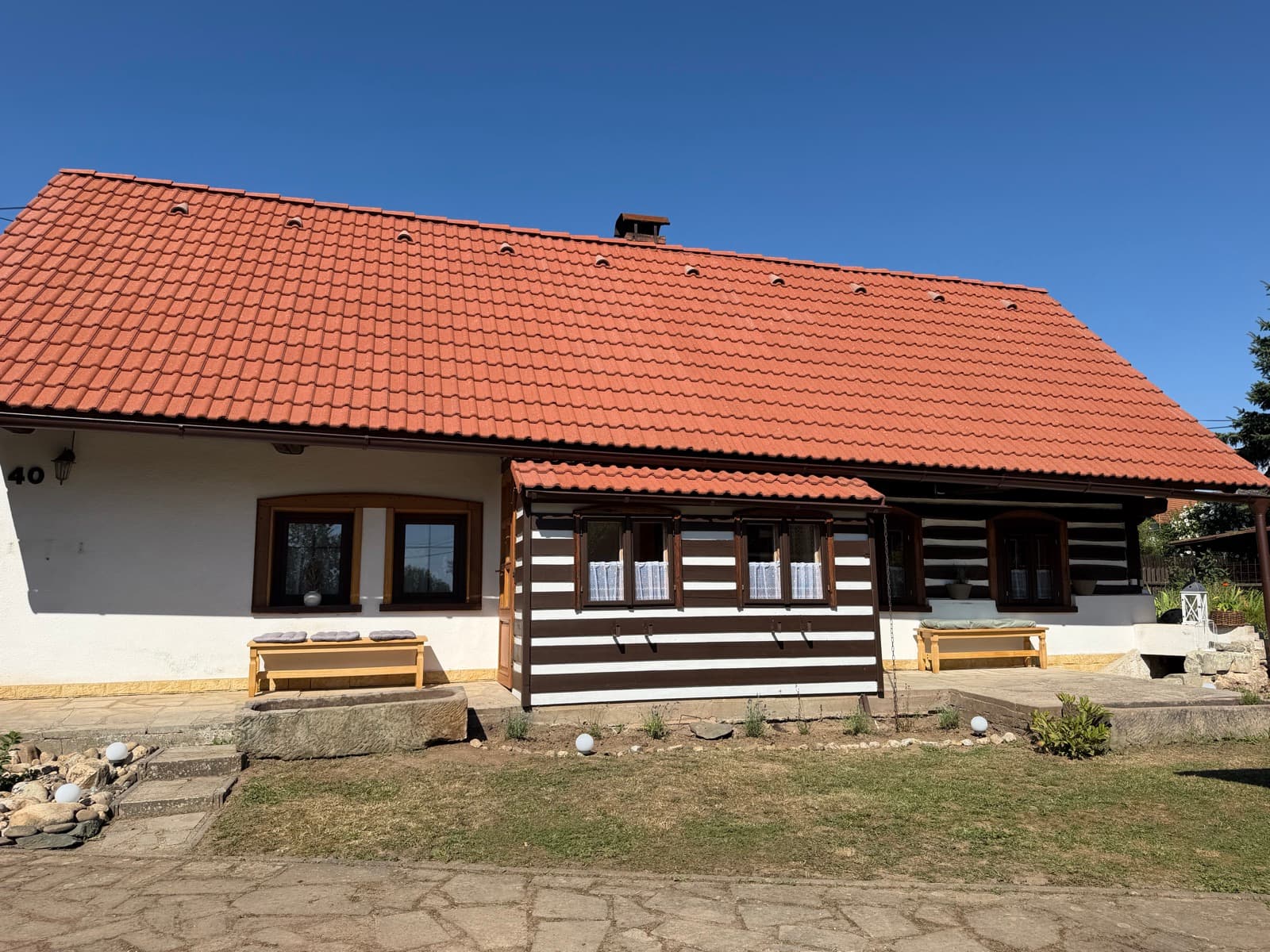 Průčelí roubenky s červenou střechou a bílými spárami
