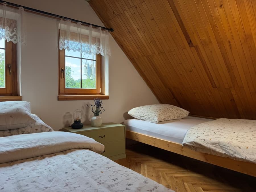 Lůžka u oken první ložnice s výhledem do zeleně
